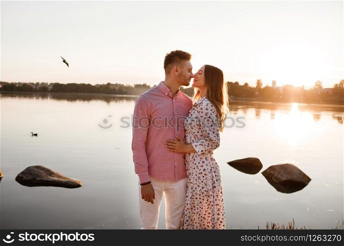 loving couple kissing on the lake at sunset. Beautiful young couple in love walking on the shore of the lake at sunset in the rays of bright light. copy space.. loving couple kissing on the lake at sunset. Beautiful young couple in love walking on the shore of the lake at sunset in the rays of bright light. copy space
