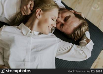 Loving couple lying and kissing on the floor at home