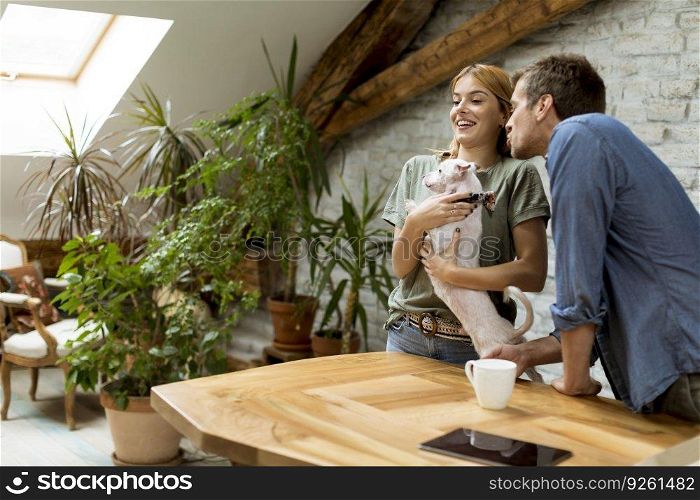 Loving couple playing with cute white dog in the room