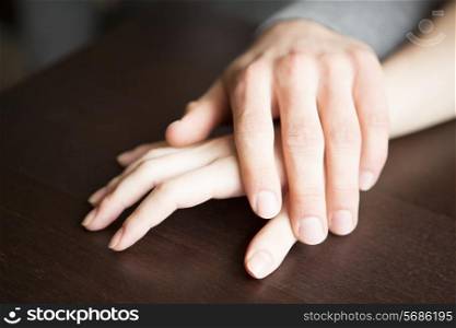 Loving couple&rsquo;s hands on table