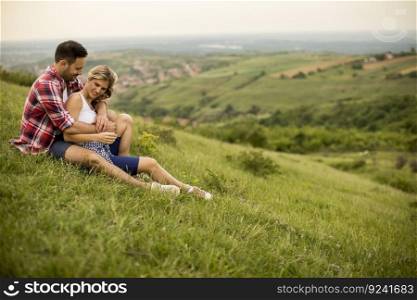 Loving couple sitting  hugged on the grass in the mountain