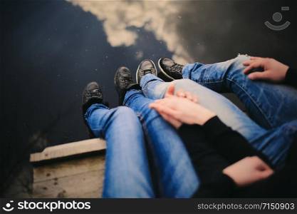 Loving couple sitting near river on bridge holding hands. Loving couple sitting near river on bridge holding hands.