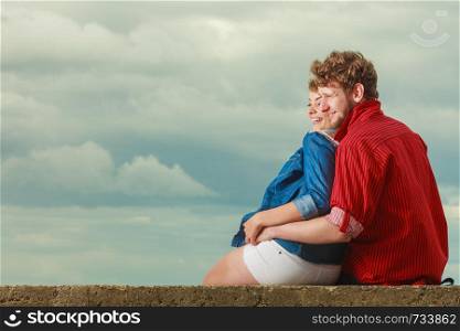 Loving couple spending leisure time together at beach sitting on sea shore hugging side view