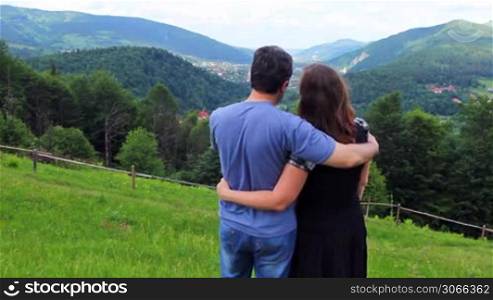 loving couple stands embracing on top and show his hands at mountain