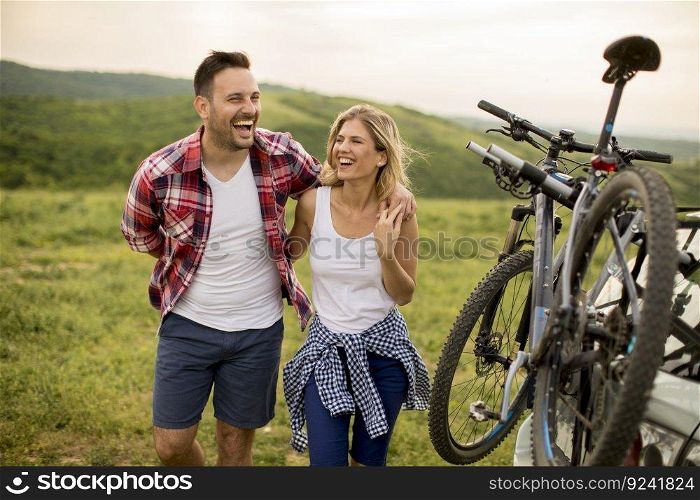 Loving couple stnding next to the car with bicycles in the nature