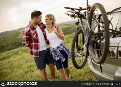 Loving couple stnding next to the car with bicycles in the nature
