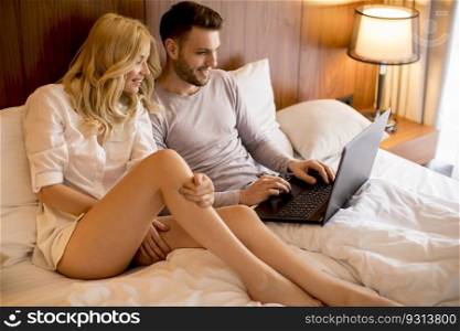 Loving couple surfing internet on laptop in the bed at home