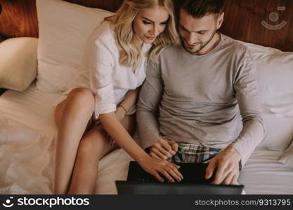 Loving couple surfing on internet at laptop in the bed at home