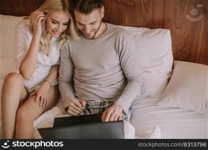 Loving couple surfing on internet at laptop in the bed at home