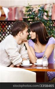 Loving couple talks behind a little table in cafe