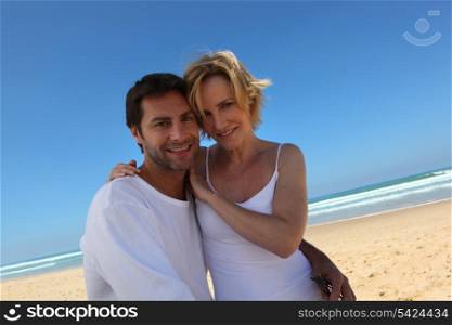 Loving couple wearing white enjoying the beach on a blue sky day