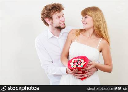 Loving couple with candy bunch bouquet flowers. Handsome man and pretty woman holding present gift. Relationship love concept.. Loving couple with candy bunch flowers. Love.