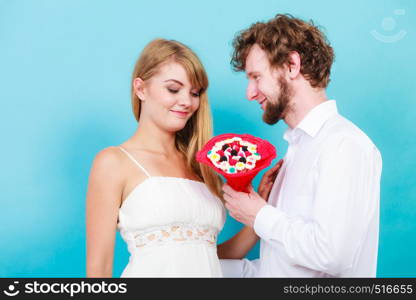 Loving couple with candy bunch bouquet flowers. Man and woman holding present gift.. Loving couple with candy bunch flowers. Love.
