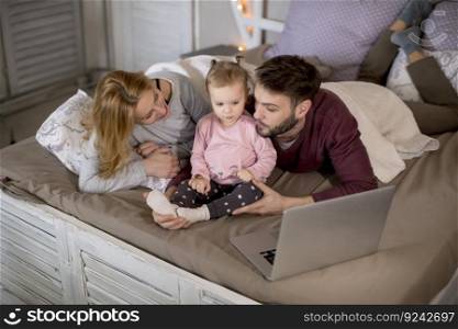 Loving family looking at a laptop lying down on bed at home