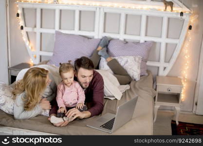 Loving family looking at a laptop lying down on bed at home