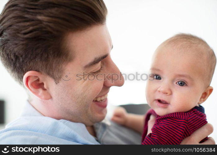 Loving Father Cuddling Cute Baby Son At Home