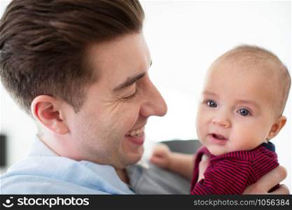 Loving Father Cuddling Cute Baby Son At Home