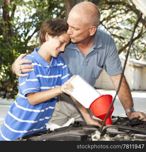 Loving father kisses his son as they work on the car engine together.