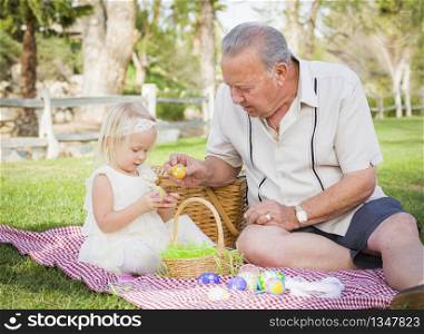 Loving Grandfather and Granddaughter Enjoying Easter Eggs on a Picnic Blanket At Park.