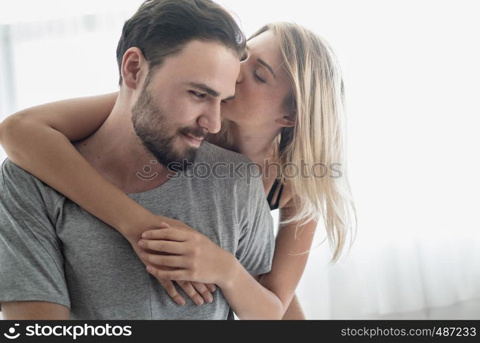 Loving happy couple in love smile and hug each other on the bed, in big bedroom, Love story concept