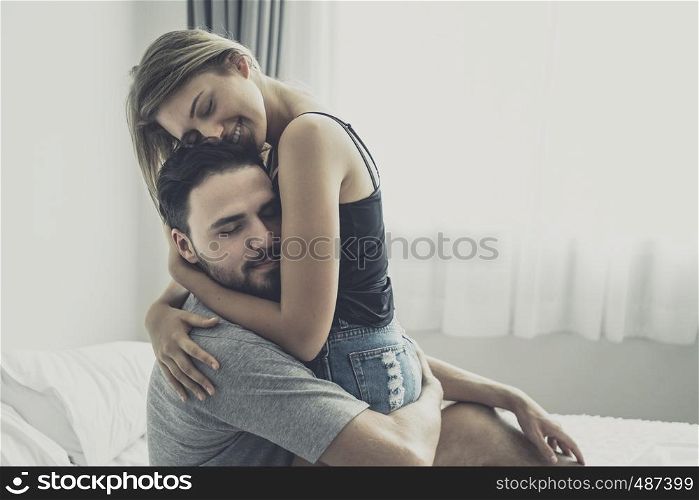 Loving happy couple in love smile and hug each other on the bed, in big bedroom, Love story concept
