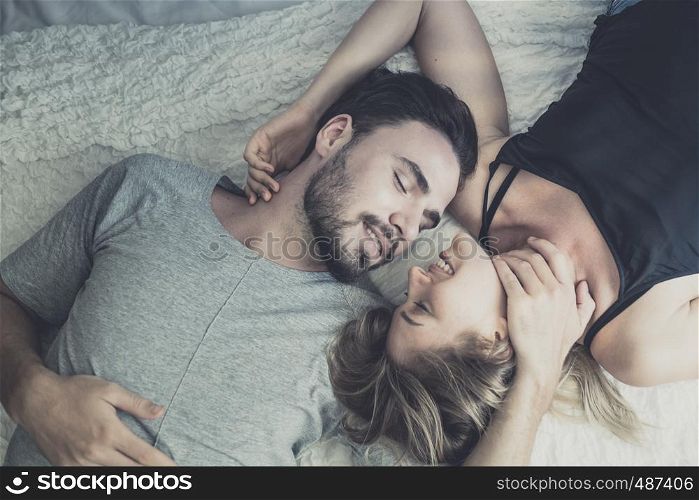 Loving happy couple in love smile and kiss her cheek on the bed, in big bedroom, Love story concept