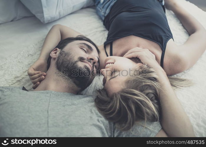 Loving happy couple in love smile and kiss her cheek on the bed, in big bedroom, Love story concept