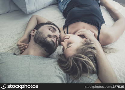 Loving happy couple in love smile and kiss her cheek on the bed, in big bedroom, Love story concept