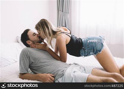 Loving happy couple in love smile kissing and hug each other on the bed, in big bedroom, Love story concept