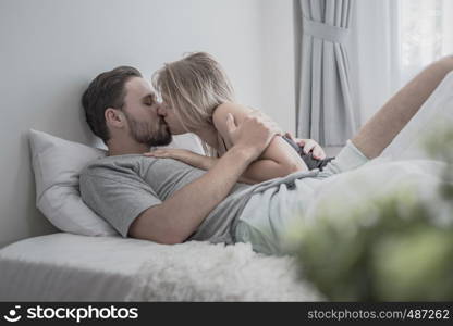 Loving happy couple in love smile kissing and hug each other on the bed, in big bedroom, Love story concept