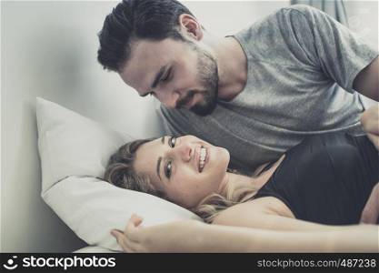 Loving happy couple in love smile, man kiss woman for wake her up on the bed, in morning, Love story concept