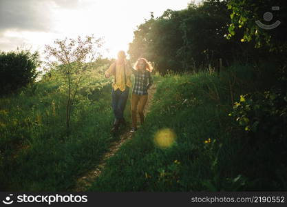 Loving hipster couple walking in the field, kissing and holding hands, hugging, lying in the grass in the summer at sunset. valentines day.. Loving hipster couple walking in the field, kissing and holding hands, hugging, lying in the grass in the summer at sunset. valentines day