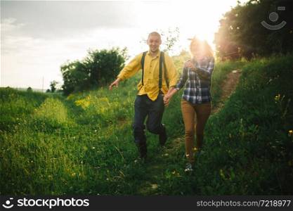 Loving hipster couple walking in the field, kissing and holding hands, hugging, lying in the grass in the summer at sunset. valentines day.. Loving hipster couple walking in the field, kissing and holding hands, hugging, lying in the grass in the summer at sunset. valentines day