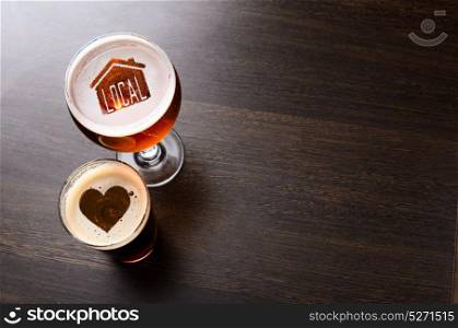 Loving local craft beer. Loving local craft beer. House and heart silhouettes in two glasses of fresh beer on pub table, view from above