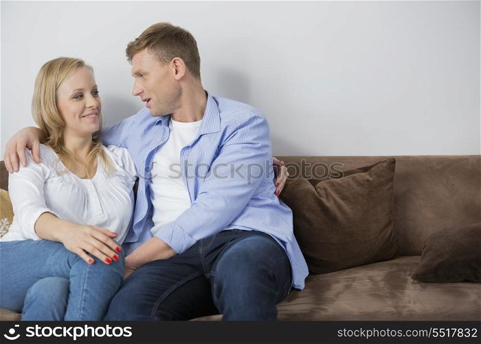 Loving mid adult couple sitting on sofa at home