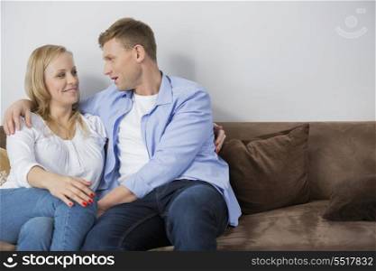 Loving mid adult couple sitting on sofa at home