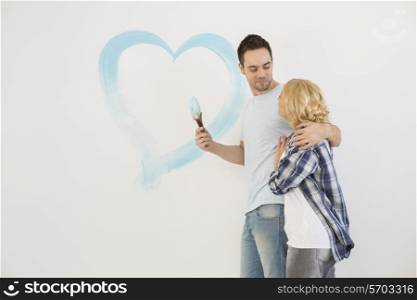 Loving mid-adult couple with painted heart on wall