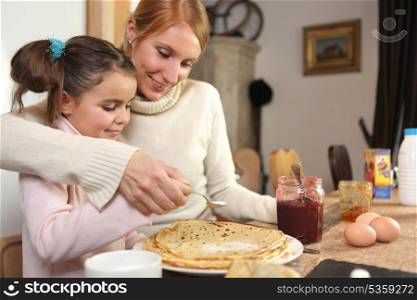 loving mother making crepes with little girl