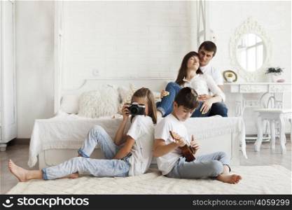 loving parent sitting bed their daughter holding camera son playing ukulele