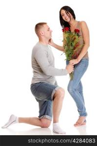 Loving Portrait of beautiful young happy smiling couple isolated - man down on his knee giving his girlfriend a rose and the girl isolated on white