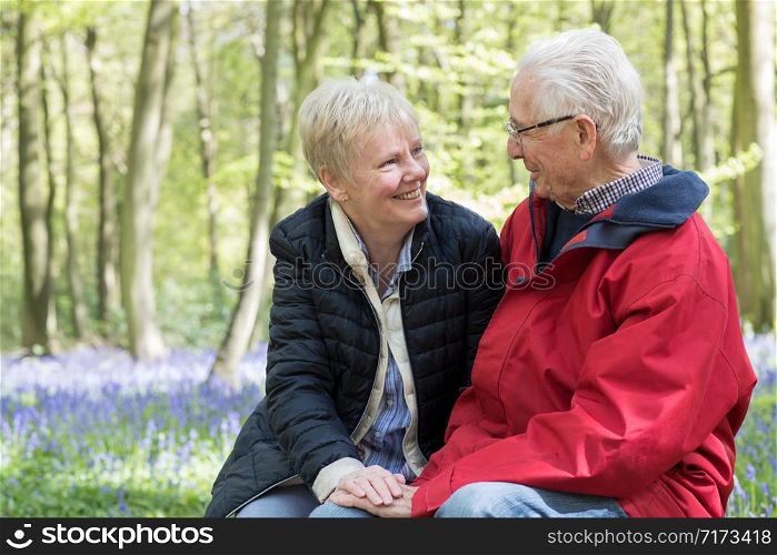 Loving Senior Couple Taking Break On Walk Through Bluebell Wood