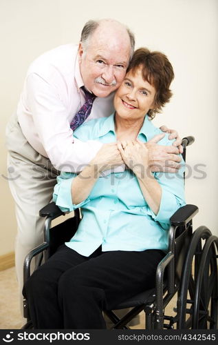 Loving, supportive husband gives his disabled wife a hug.