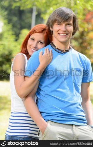 Loving teenage girlfriend embracing her boyfriend in sunny park