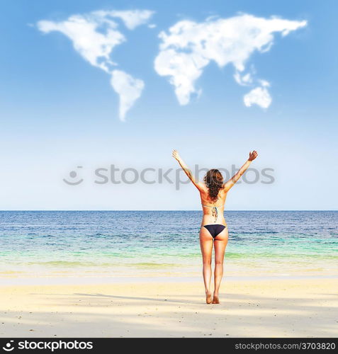 loving travelling. young woman on beach is trying to embrace continents shaped clouds