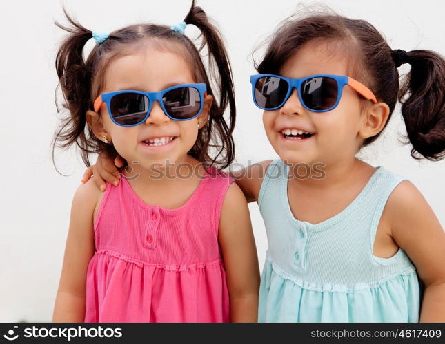 Loving twin sisters two years with sunglasses outdoors playing