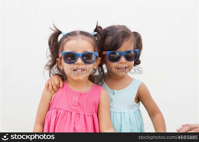 Loving twin sisters two years with sunglasses outdoors playing