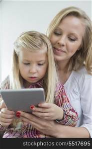 Loving woman with daughter using digital tablet at home