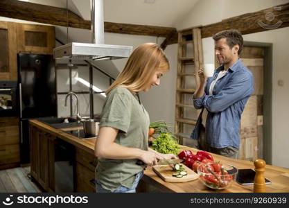 Loving young couple cutting vegetables together in the rustic kitchen