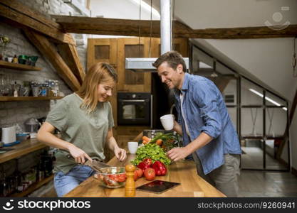 Loving young couple cutting vegetables together in the rustic kitchen