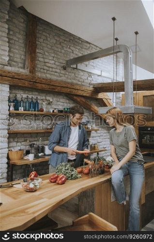 Loving young couple cutting vegetables together in the rustic kitchen